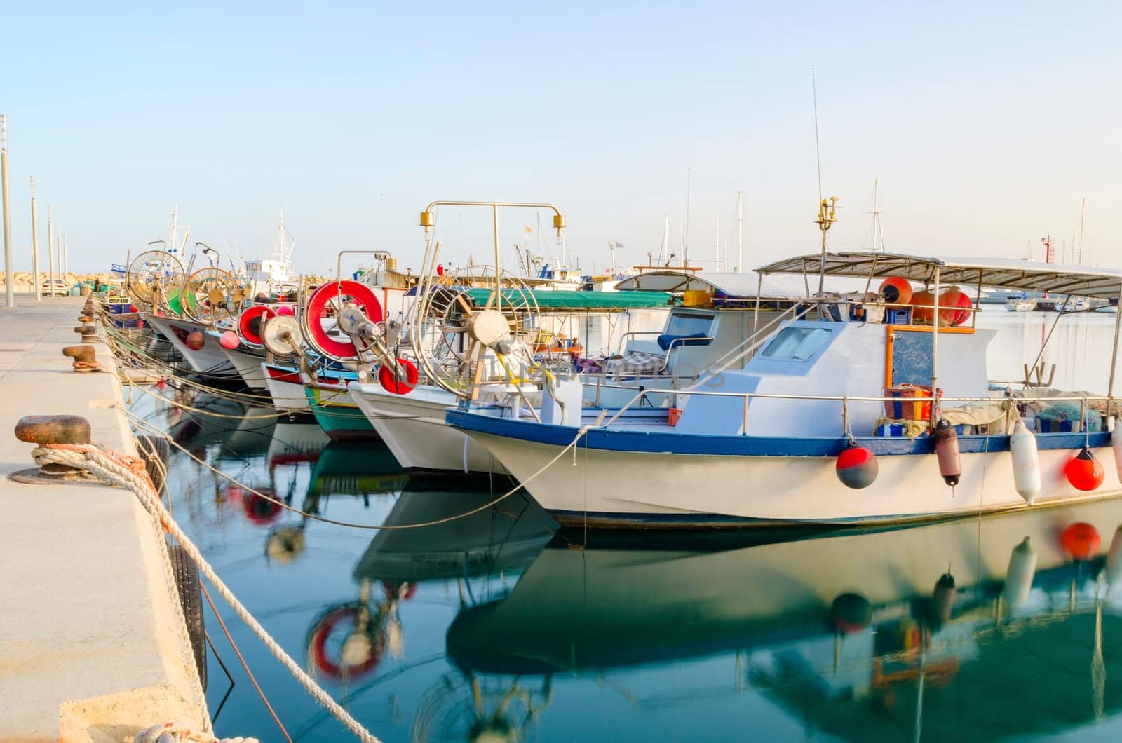 Fishing boats docked at the Limassol old port in Cyprus, next to the Marina part of the ports authority. A view of the harbor, the mediterranean sea, the water, boat and fish nets and fishing equipment.