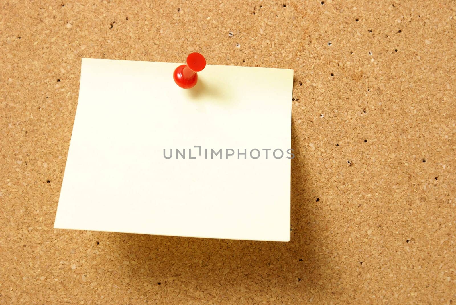 A blank note is pinned to a corkboard.