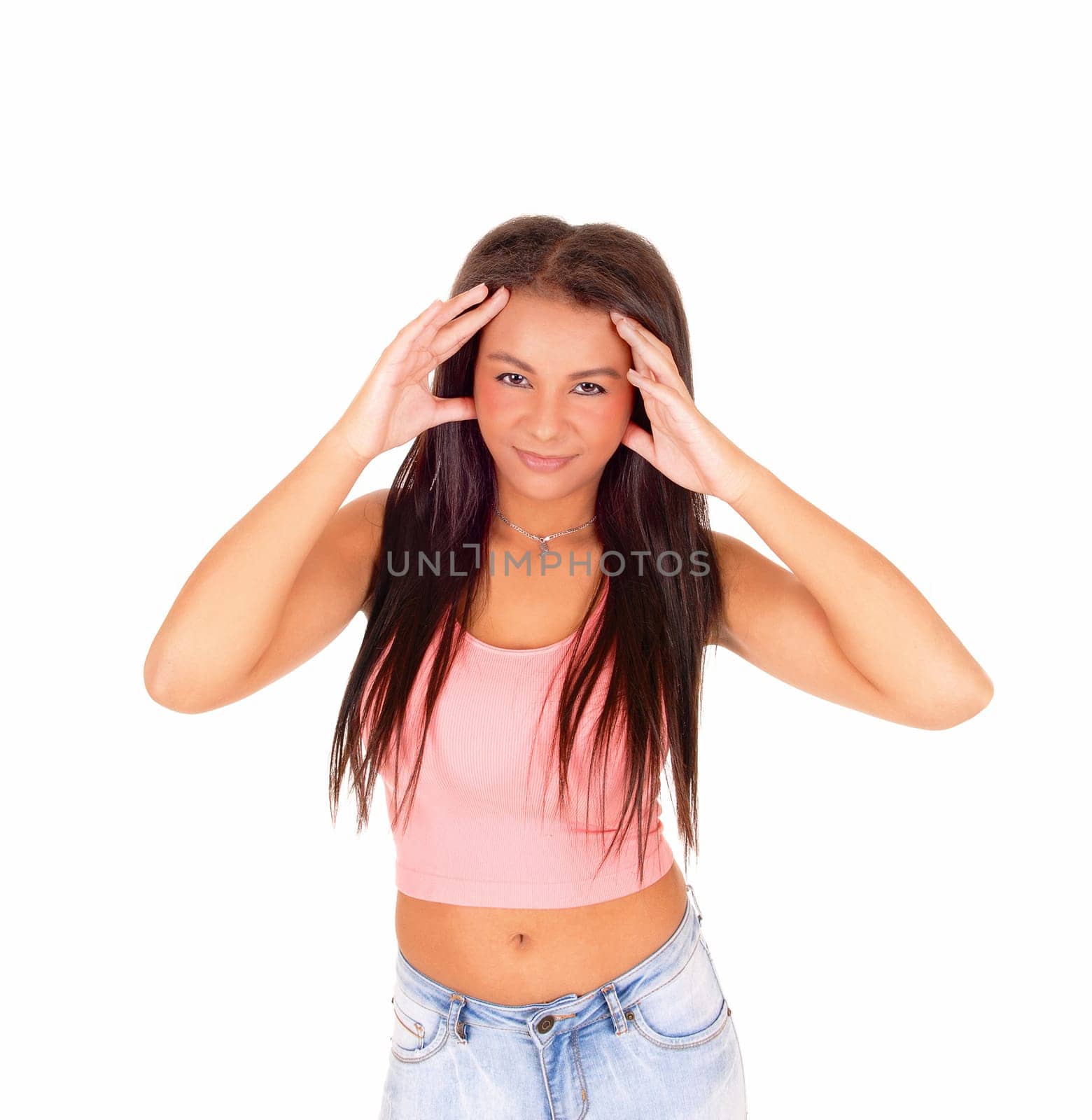 A picture of a young pretty woman standing in jeans and a pink top, .with her finger at her head with headache, isolated on white background..