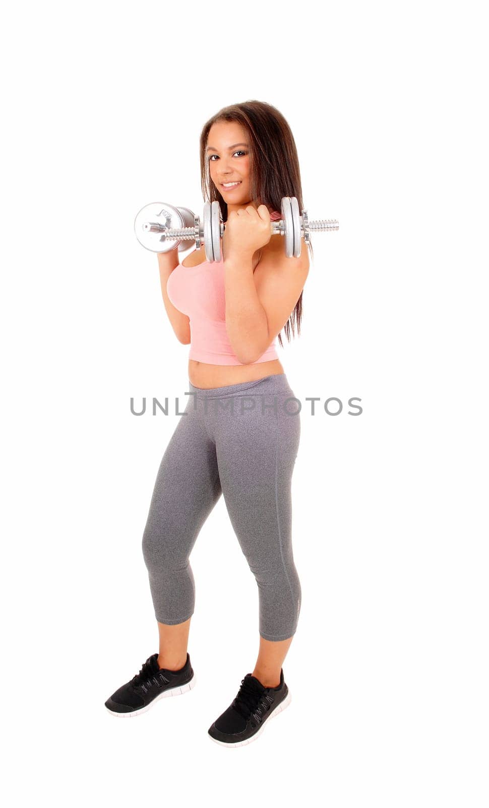 A pretty woman in grey tights and pink top standing isolated for white .background, lifting dumbbell's. .