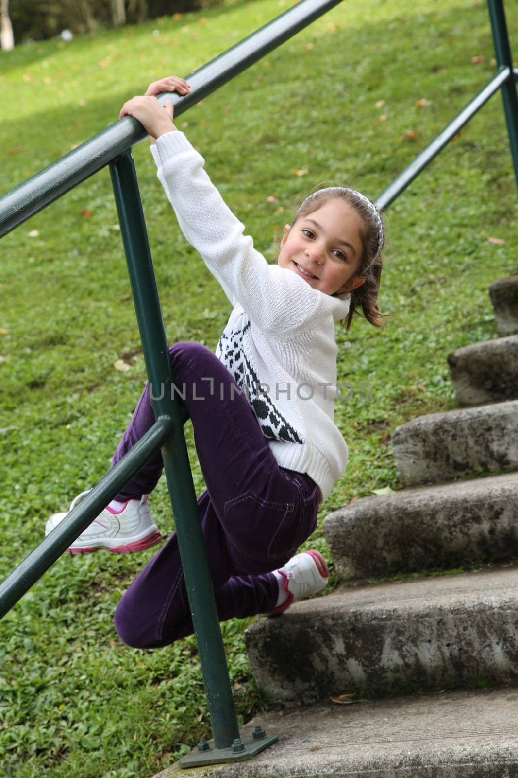 Happy little girl doing gymnastics on metal railing