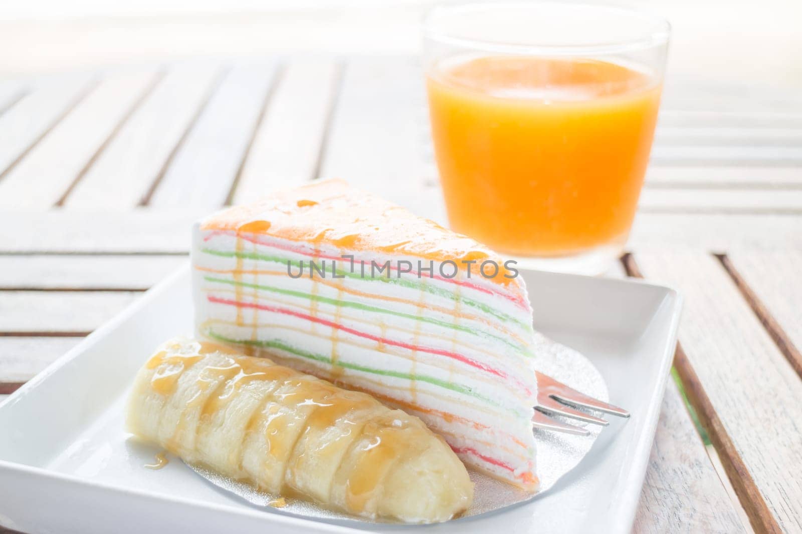 Energy charge dessert with banana caramel crepe cake and fresh orange juice, stock photo