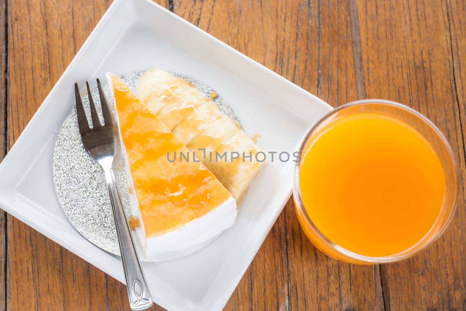 Banana caramel crepe cake and orange juice on wooden table, stock photo
