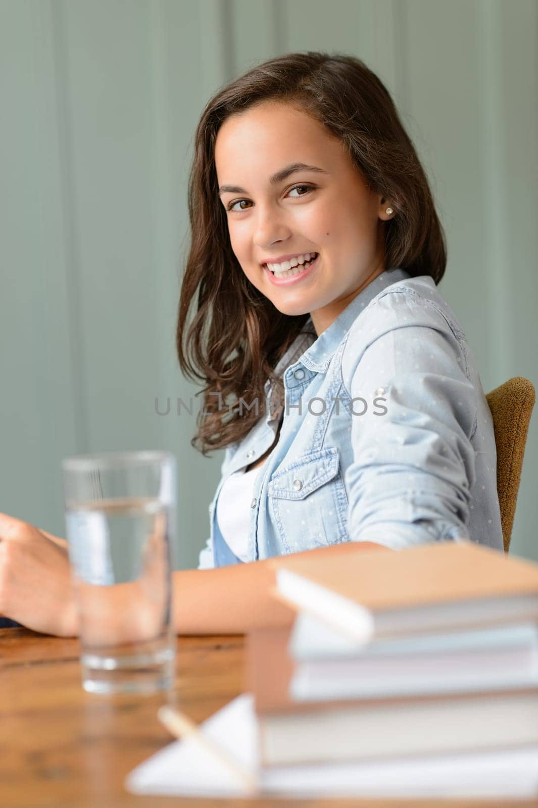 Smiling teenage girl student at home books side view