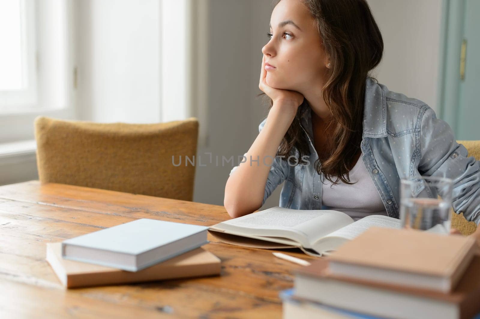 Bored student girl sitting home living room looking away read book