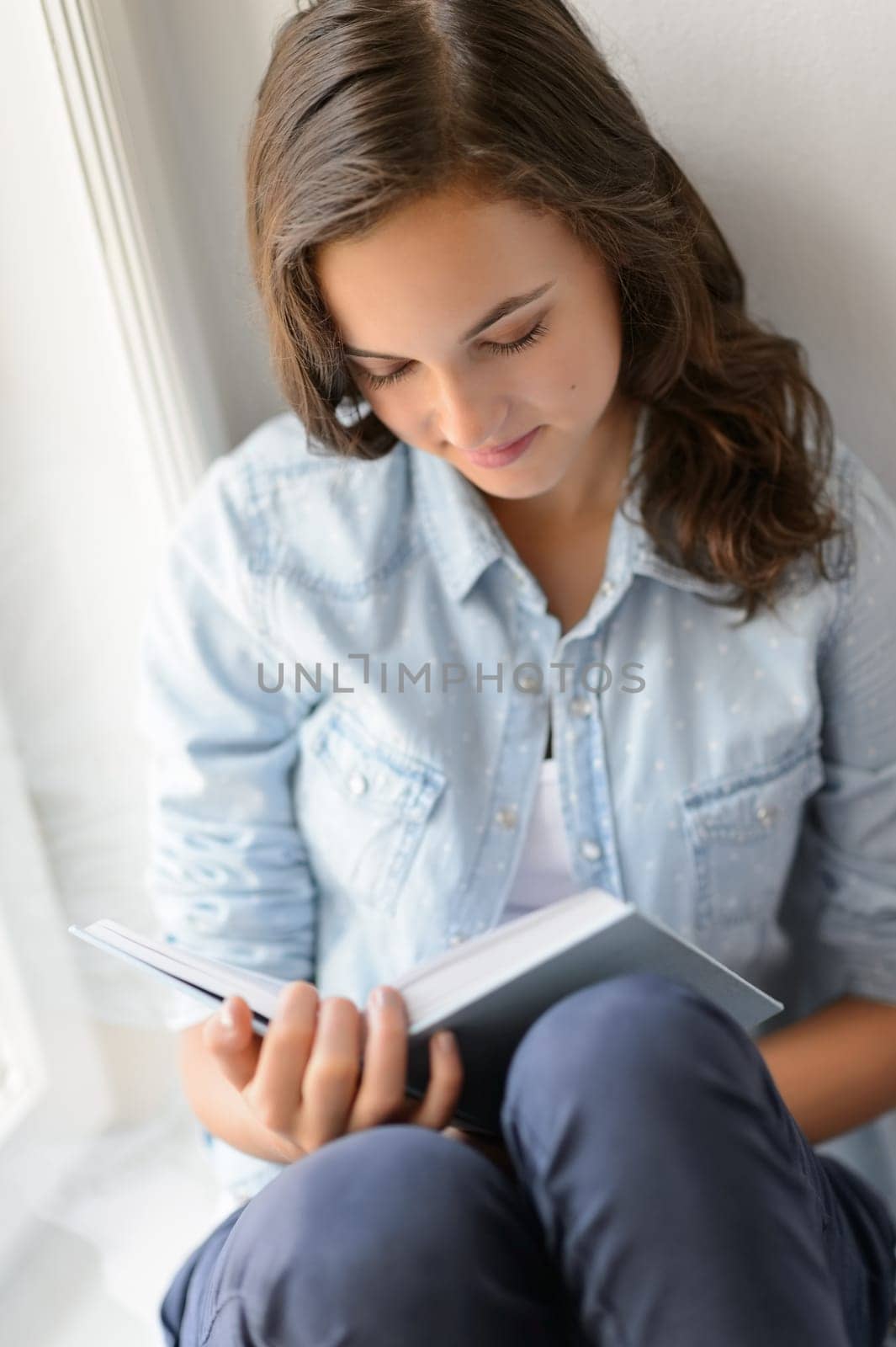 Teenage girl reading book sitting by window enjoy novel