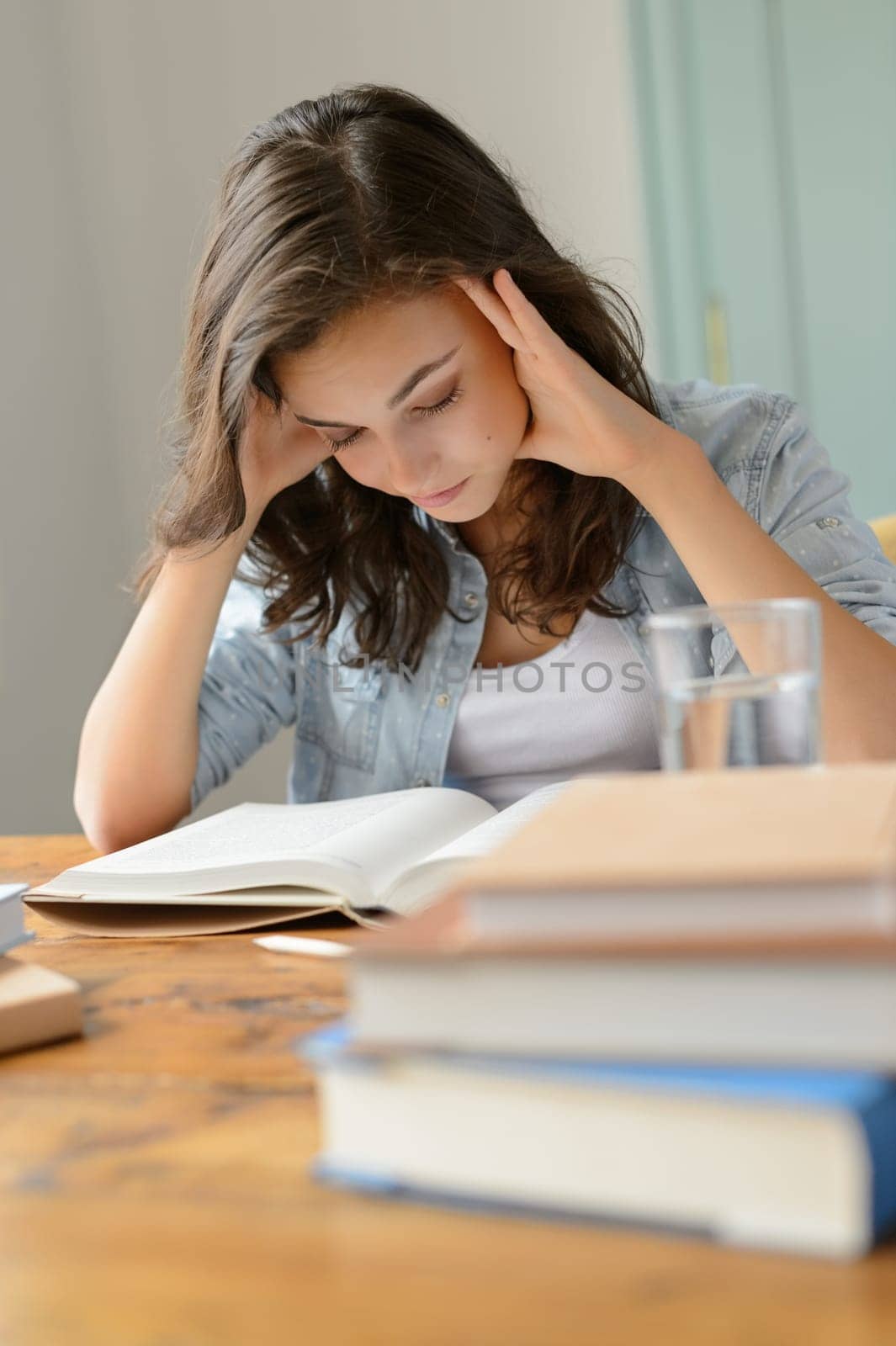 Student teenage girl concentrate reading book home holding her head