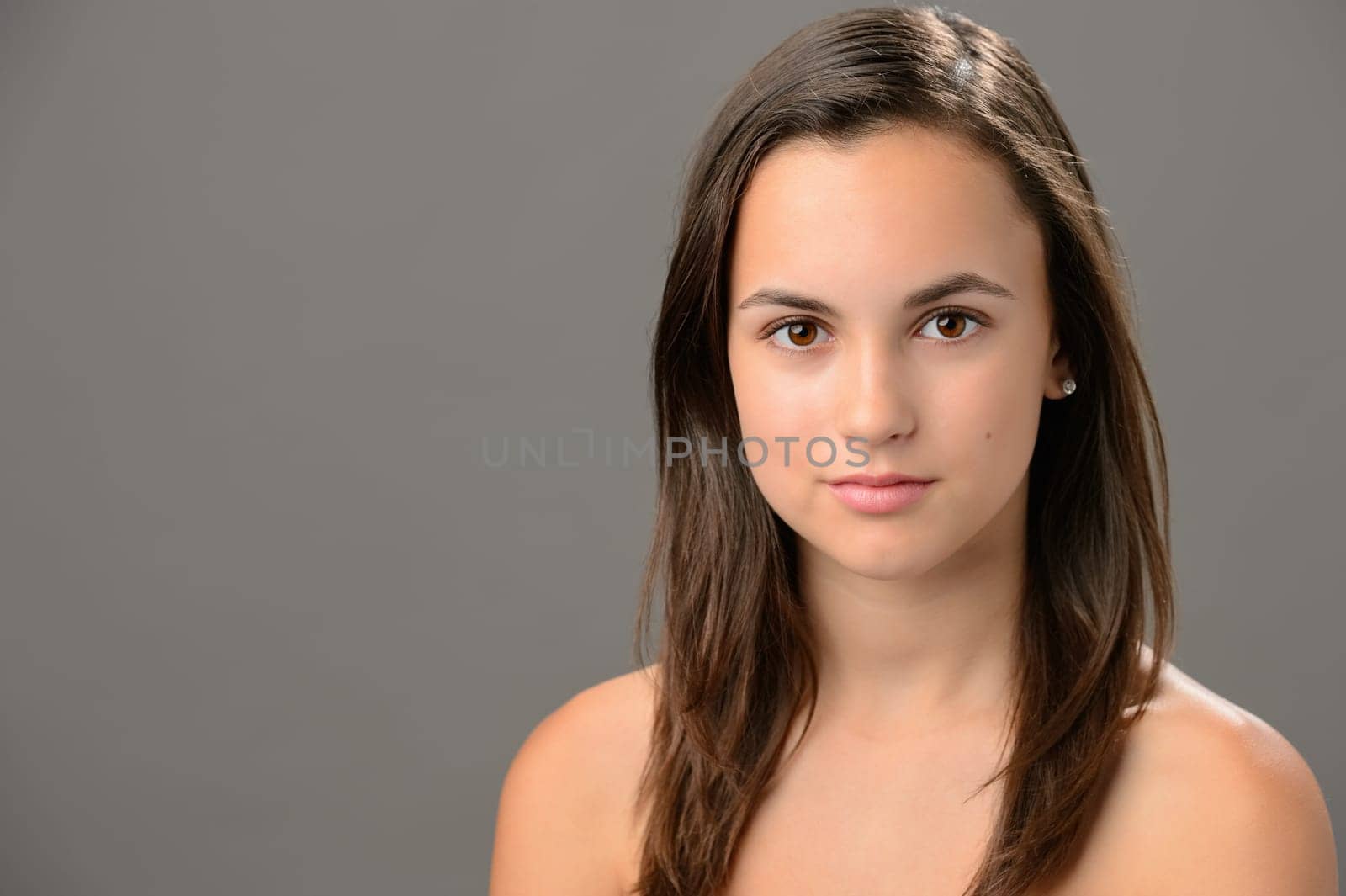 Teenage girl skin beauty portrait natural brunette on gray background