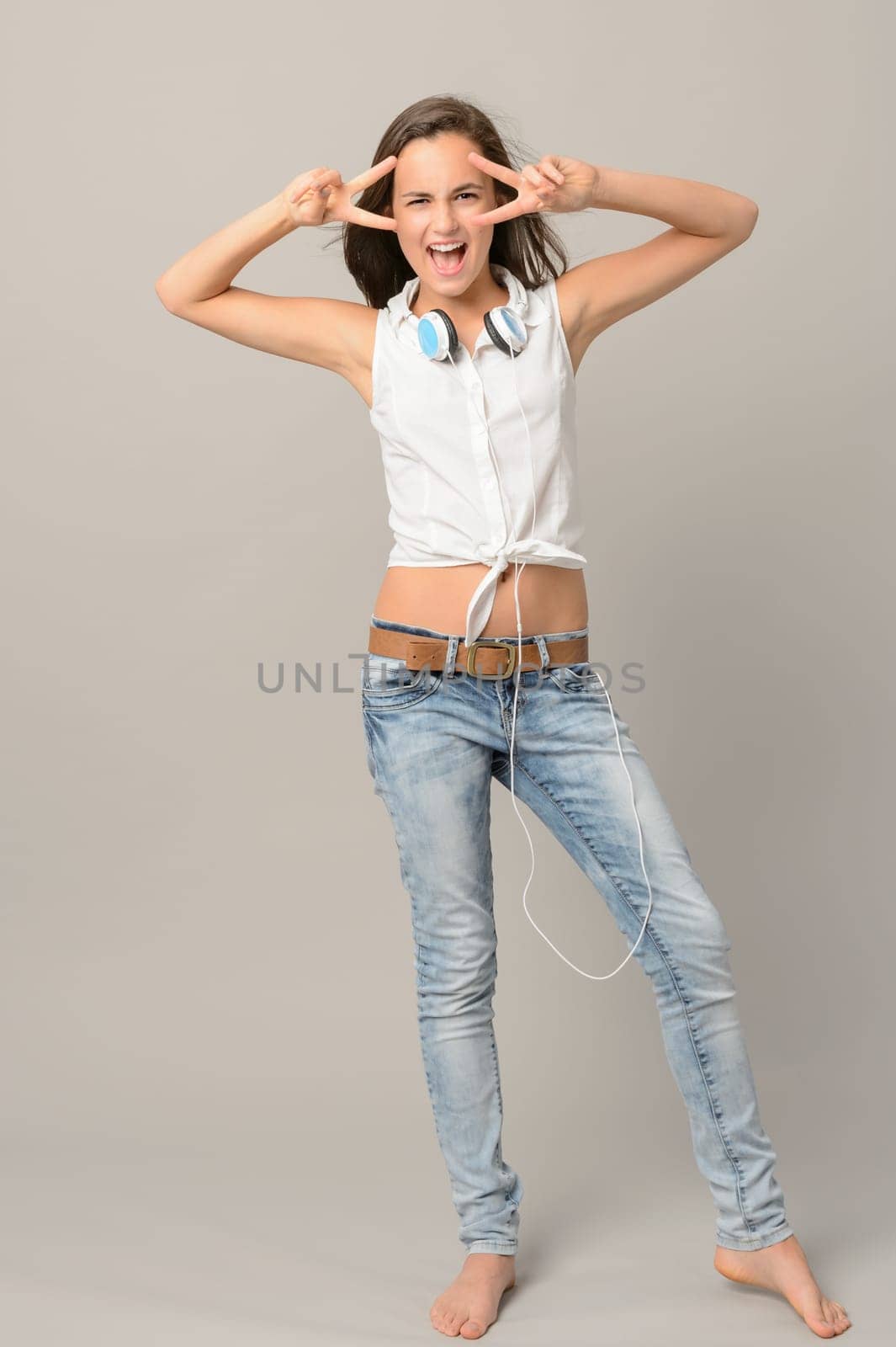 Singing teenager girl dancing full length on gray background