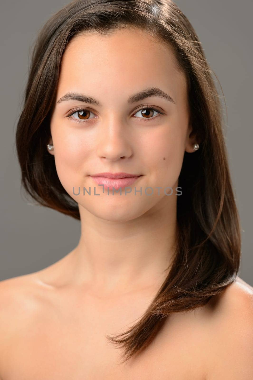 Beautiful teenage girl cosmetics skin care brunette portrait on gray