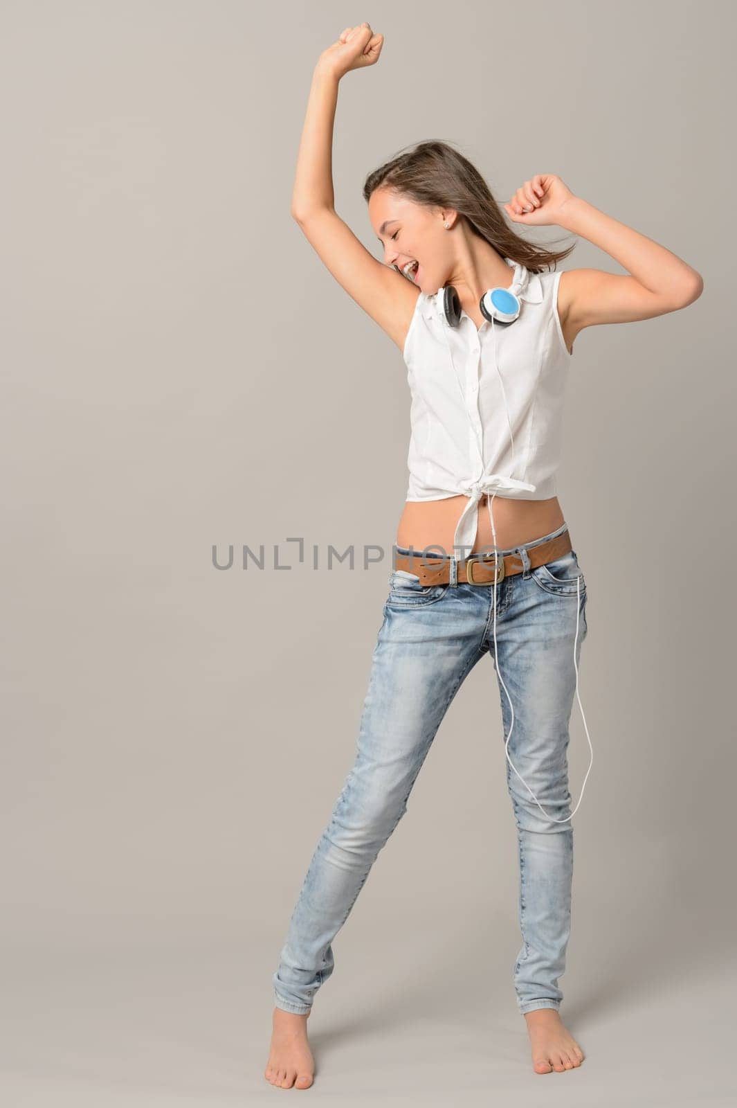 Teenage girl dancing singing enjoy music full length on gray background