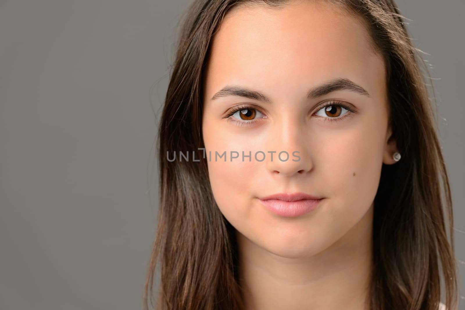 Teenage girl beauty face cosmetics brunette close-up on gray