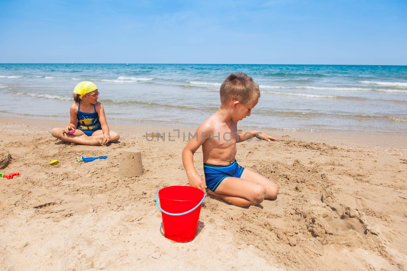 Kids playing on the beach and building sandcastle