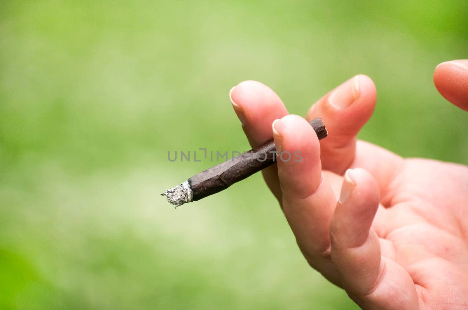 Female hand holding a lighted hand-rolled cigarette