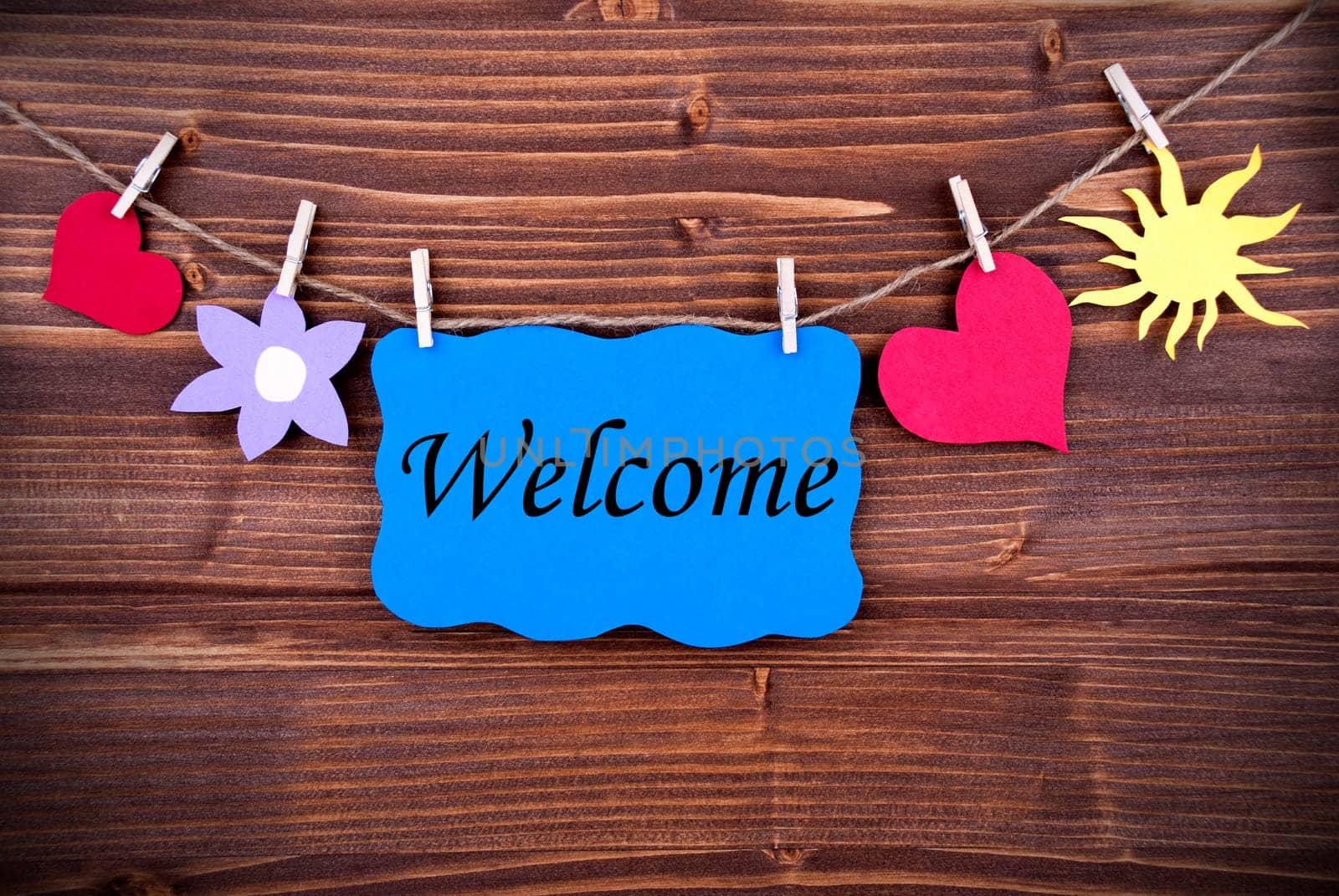 The Word Welcome on a Blue Label Hanging on a Line with Different Symbols