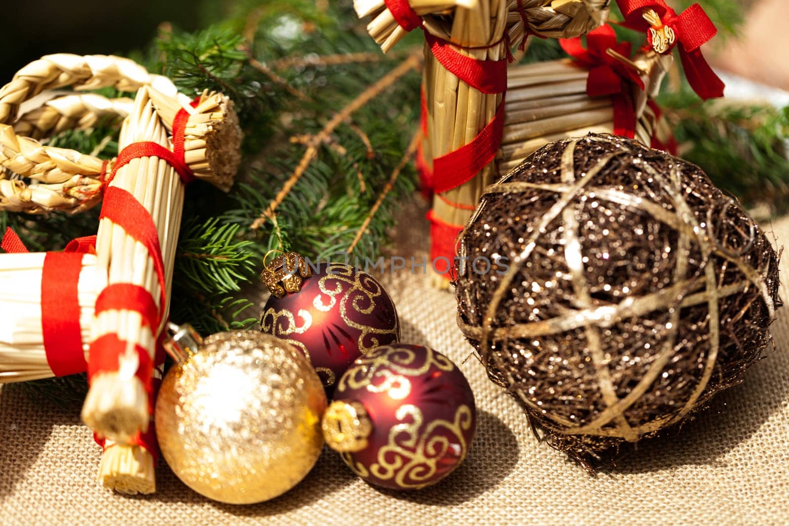 Decoration for Christmas with red and gold Christmas tree balls in front of green fir branches in the background