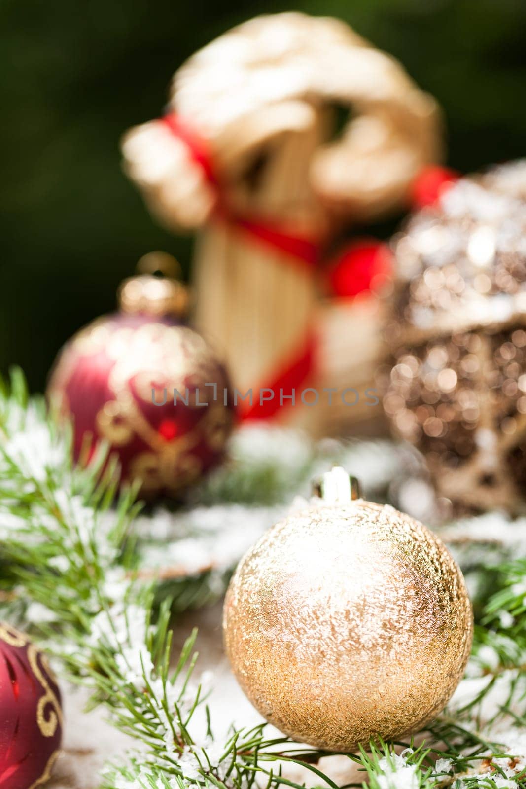 golden Christmas tree balls glittering on tannin branches with snow as macro detail