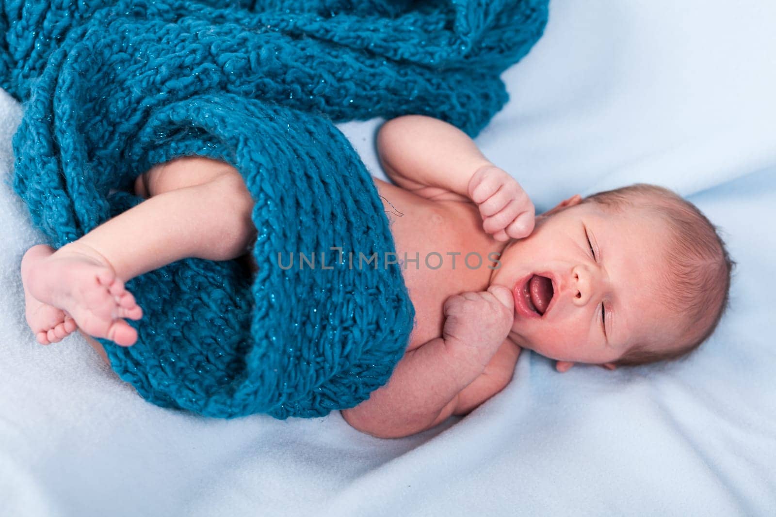 Newborn baby wrapped in a scarf sleeps naked as a close-up