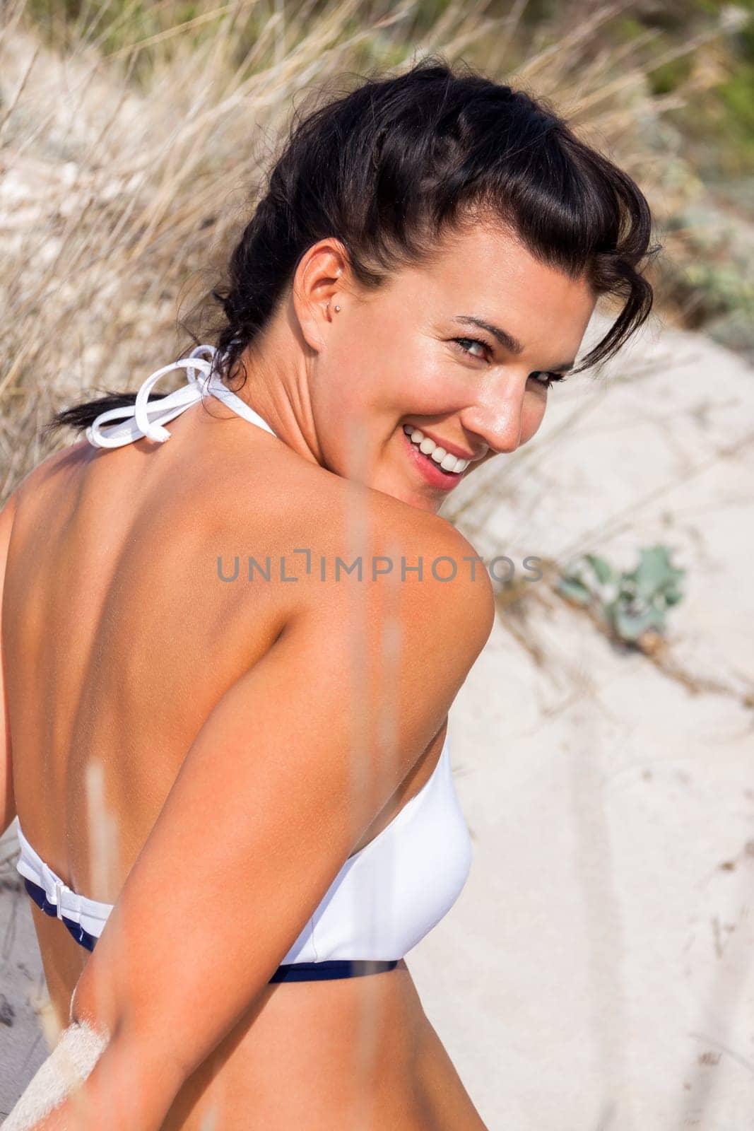 Young attractive woman in bikini in summer on the beach on vacation with blue hommel