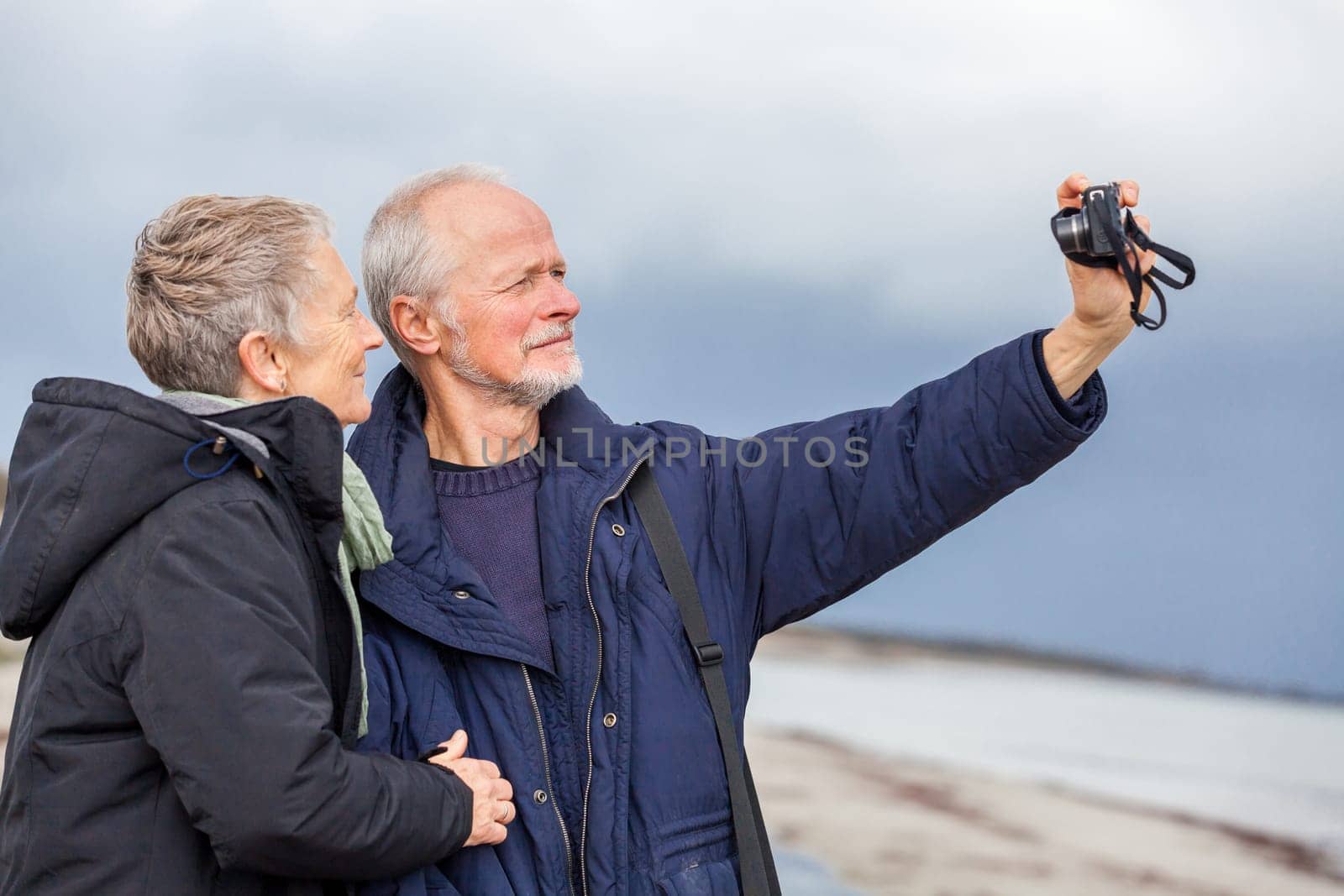older adult couple seniors happy to take self-portrait photograph with digital camera on vacation