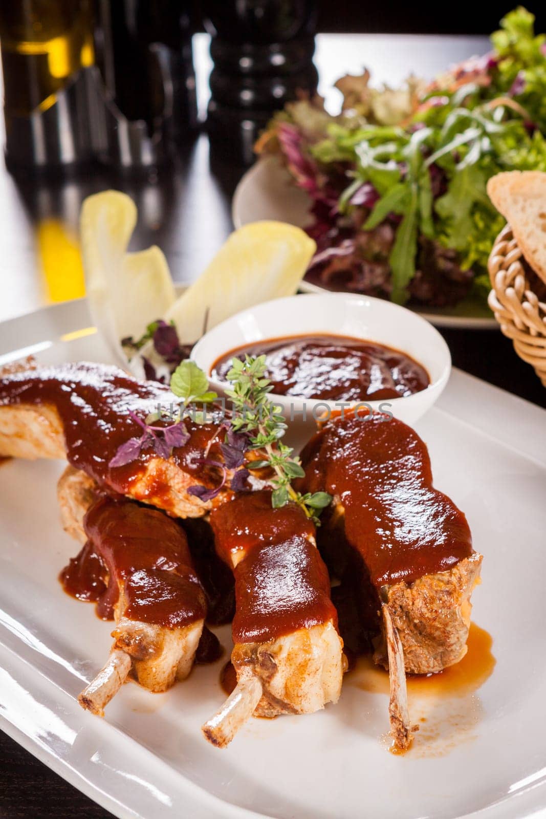 Grilled pork ribs Spareribs with barbecue sauce marinade and herb salad on a plate
