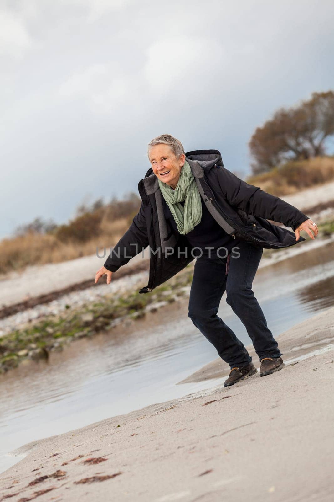 happy active older woman pensioner senior in the open at the sea in autumn