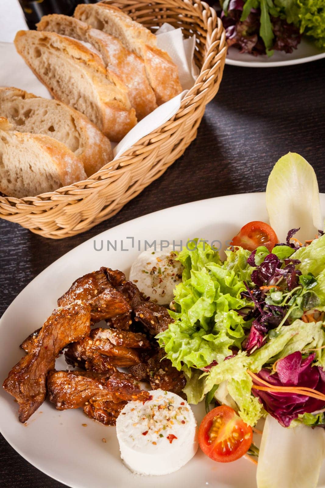 Fresh salad with fresh goat cheese and fried beef strips served on a plate