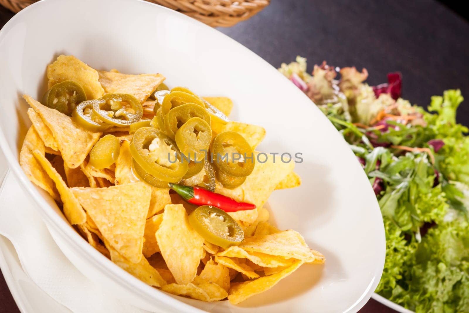 Bowl with nachos tortillas with pepperoni and fresh tomato salsa in a plate
