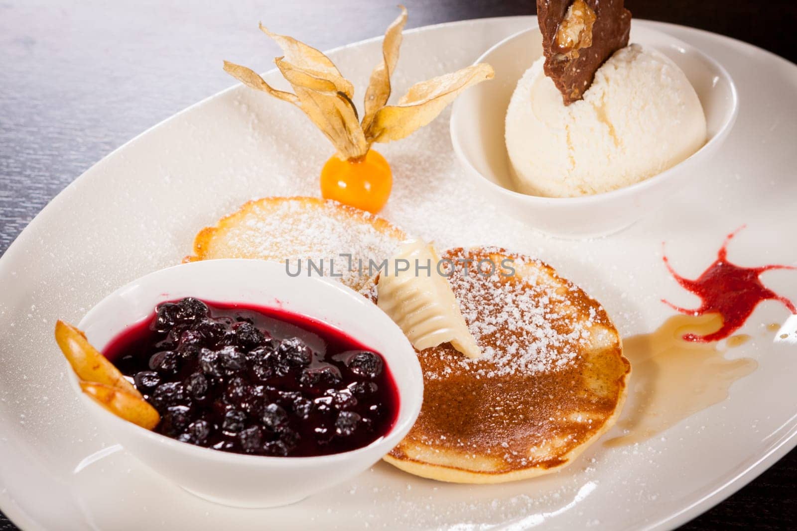 Delicious sweet pancakes as desser with vanilla ice cream prepared on a white plate