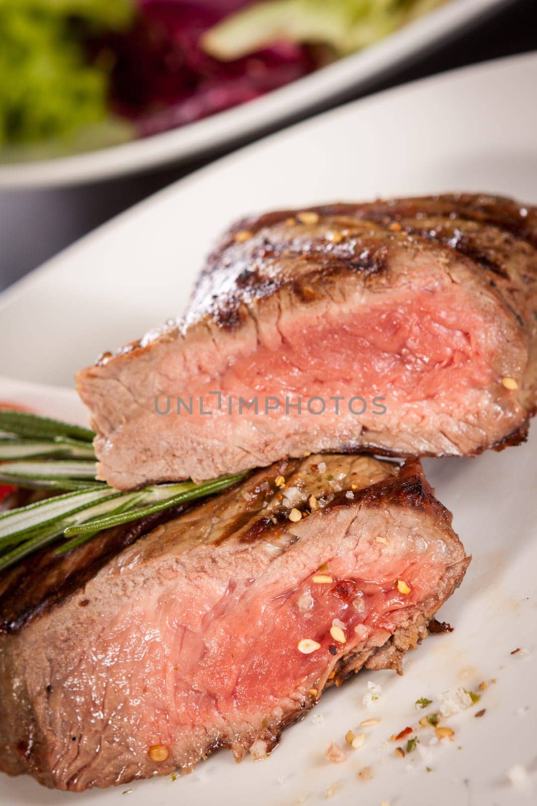 Medium fried beef steak fillet with pepper and rosemary sliced on a plate