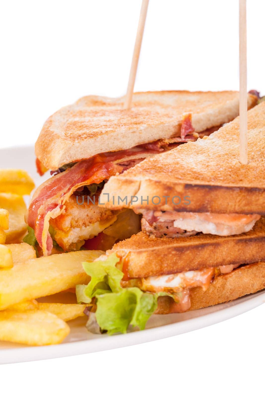 Club sandwich on toasted white bread with bacon and fries fried fries on a plate isolated against a white background