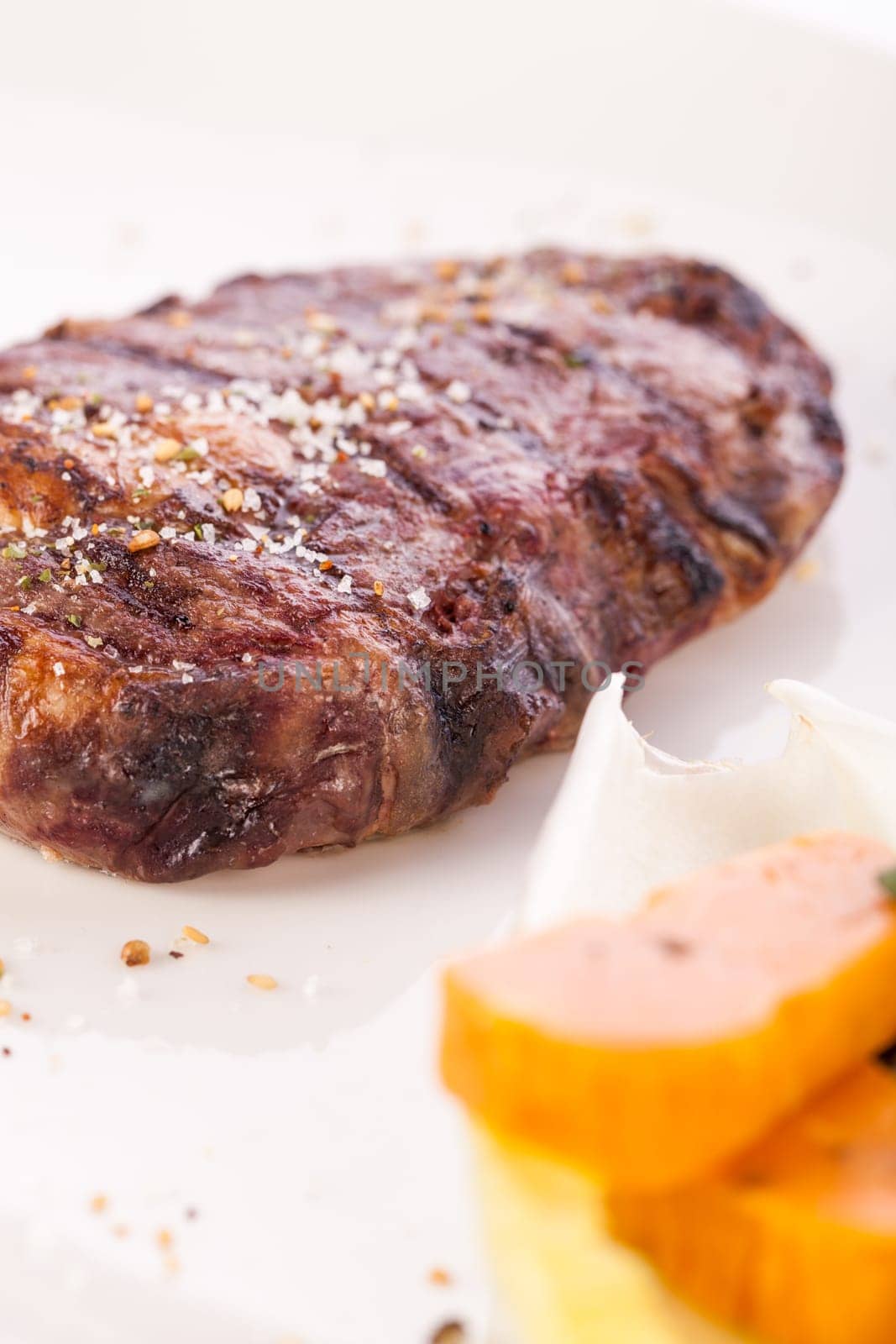 Succulent grilled beef fillet steak with homemade herb butter on a plate isolated against a white background