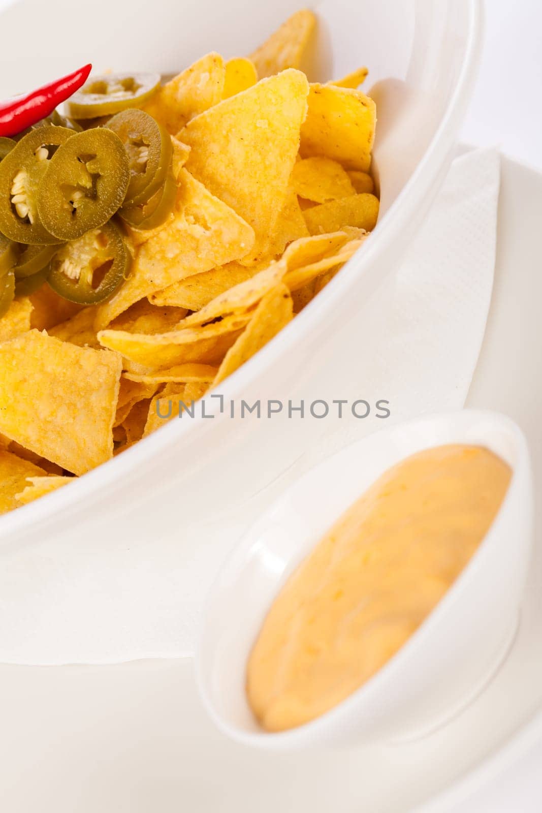Bowl with nachos tortillas with pepperoni and fresh tomato salsa in a plate insulated against a white background