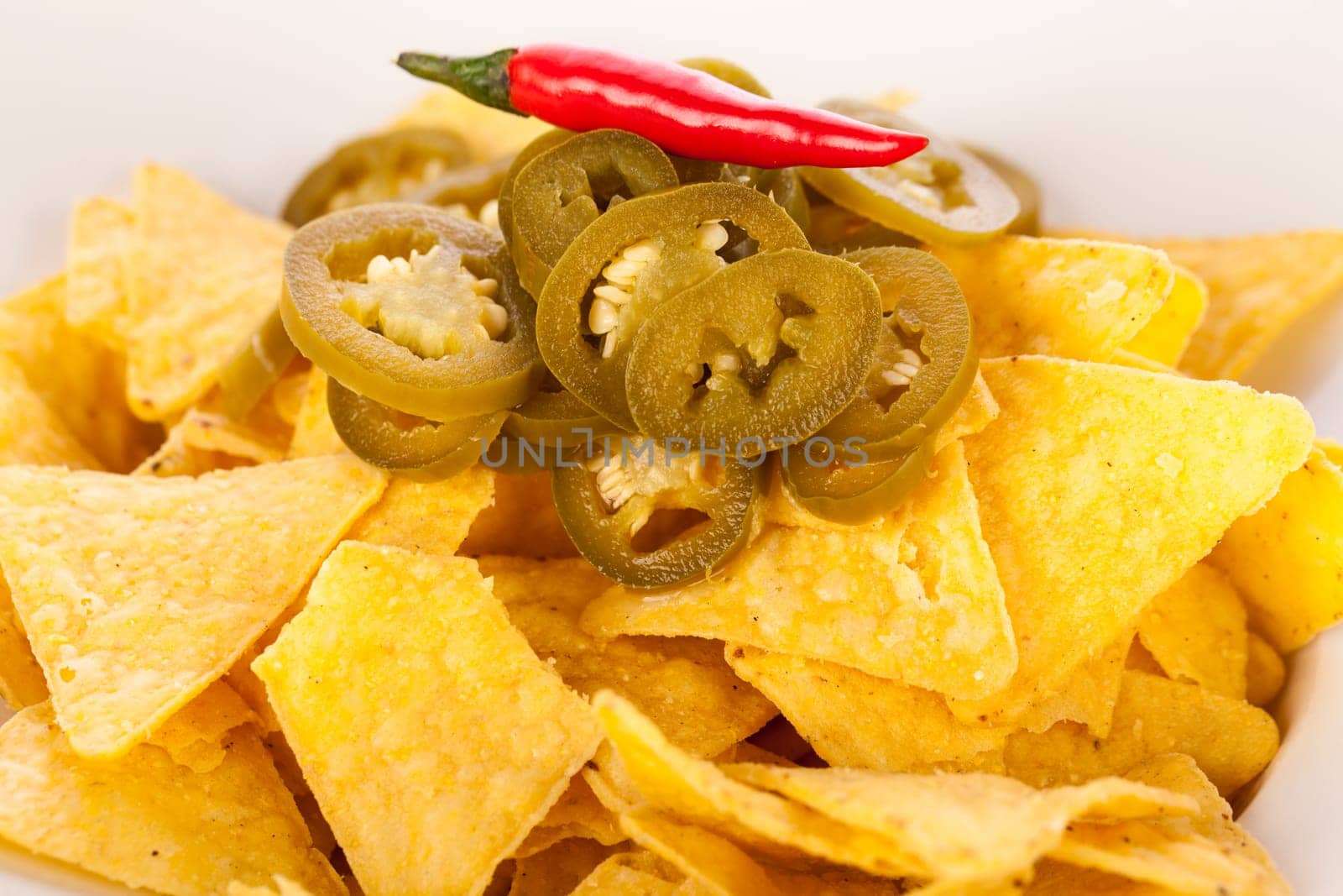 Bowl with nachos tortillas with pepperoni and fresh tomato salsa in a plate insulated against a white background
