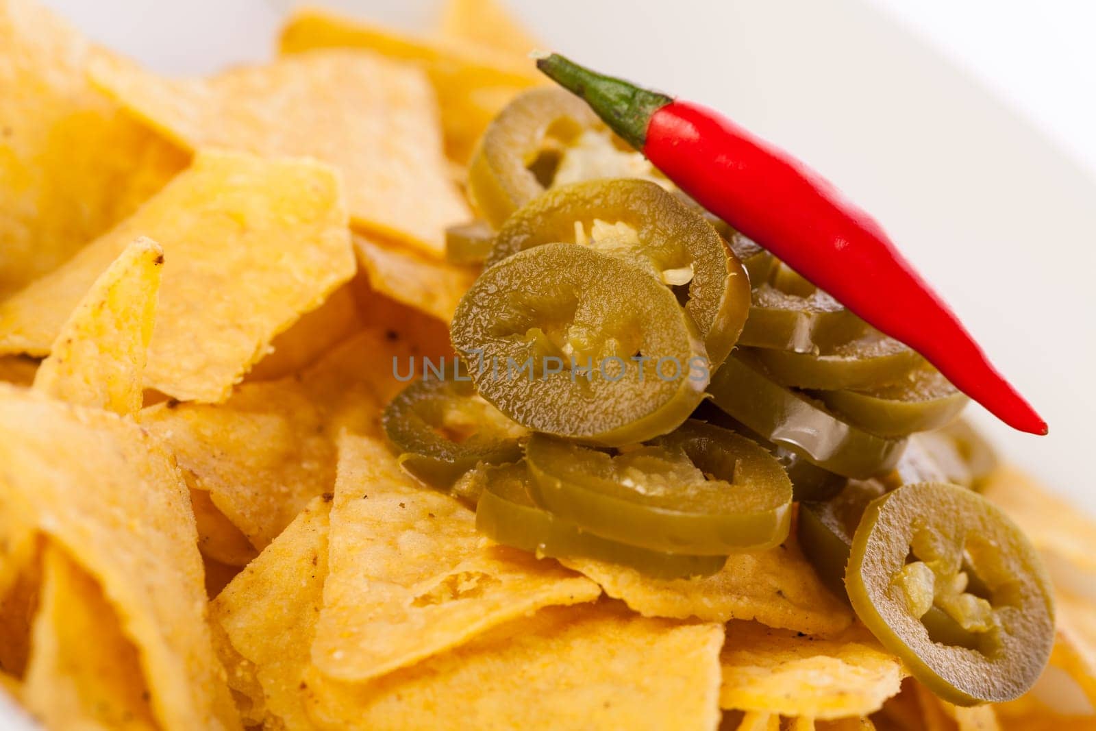 Bowl with nachos tortillas with pepperoni and fresh tomato salsa in a plate insulated against a white background
