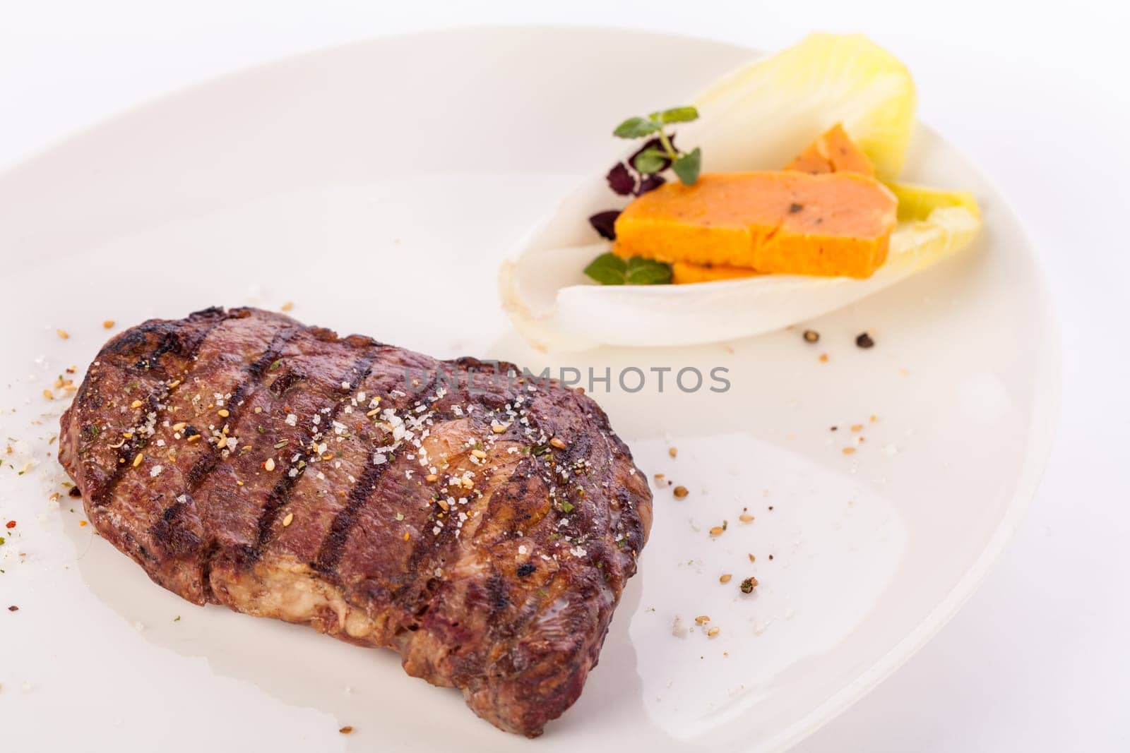 Succulent grilled beef fillet steak with homemade herb butter on a plate isolated against a white background