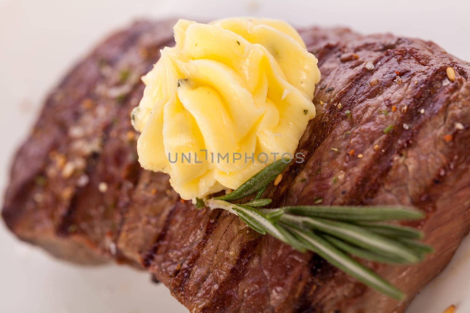 Succulent grilled beef fillet steak with homemade herb butter on a plate isolated against a white background