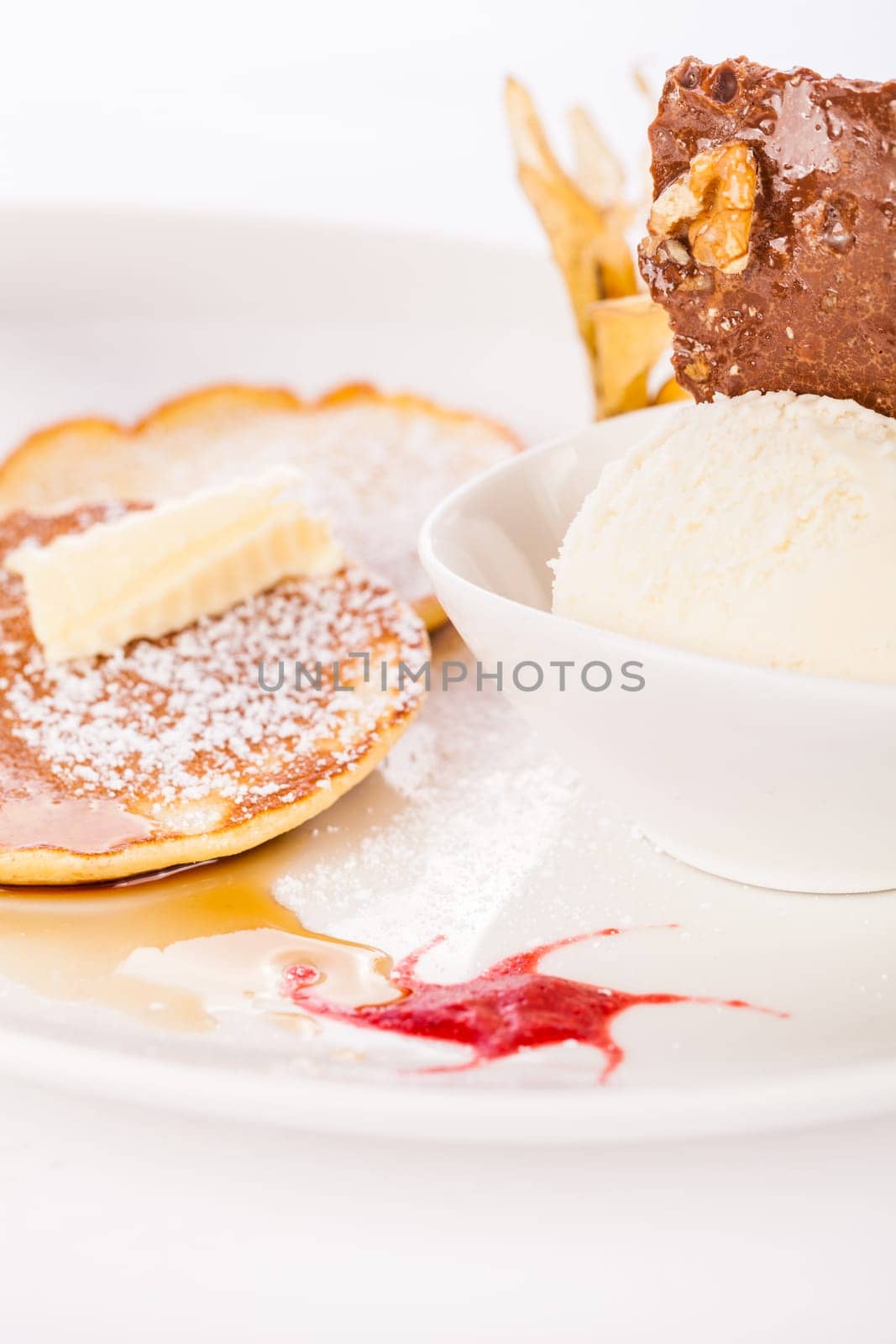 Delicious sweet pancakes as desser with vanilla ice cream prepared on a white plate insulated against a white background
