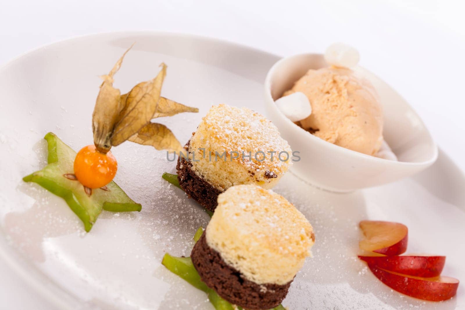 Brownie chocolate brownie with ice cream and plums prepared on a plate insulated against a white background