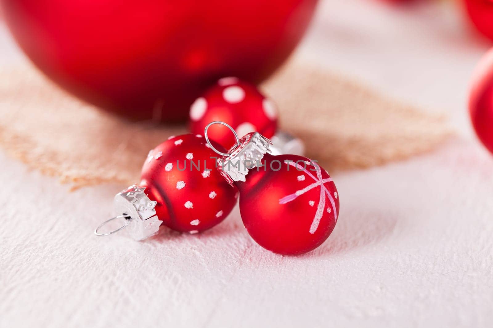 large and small red Christmas tree balls on a wooden board with a jutesack as a close-up