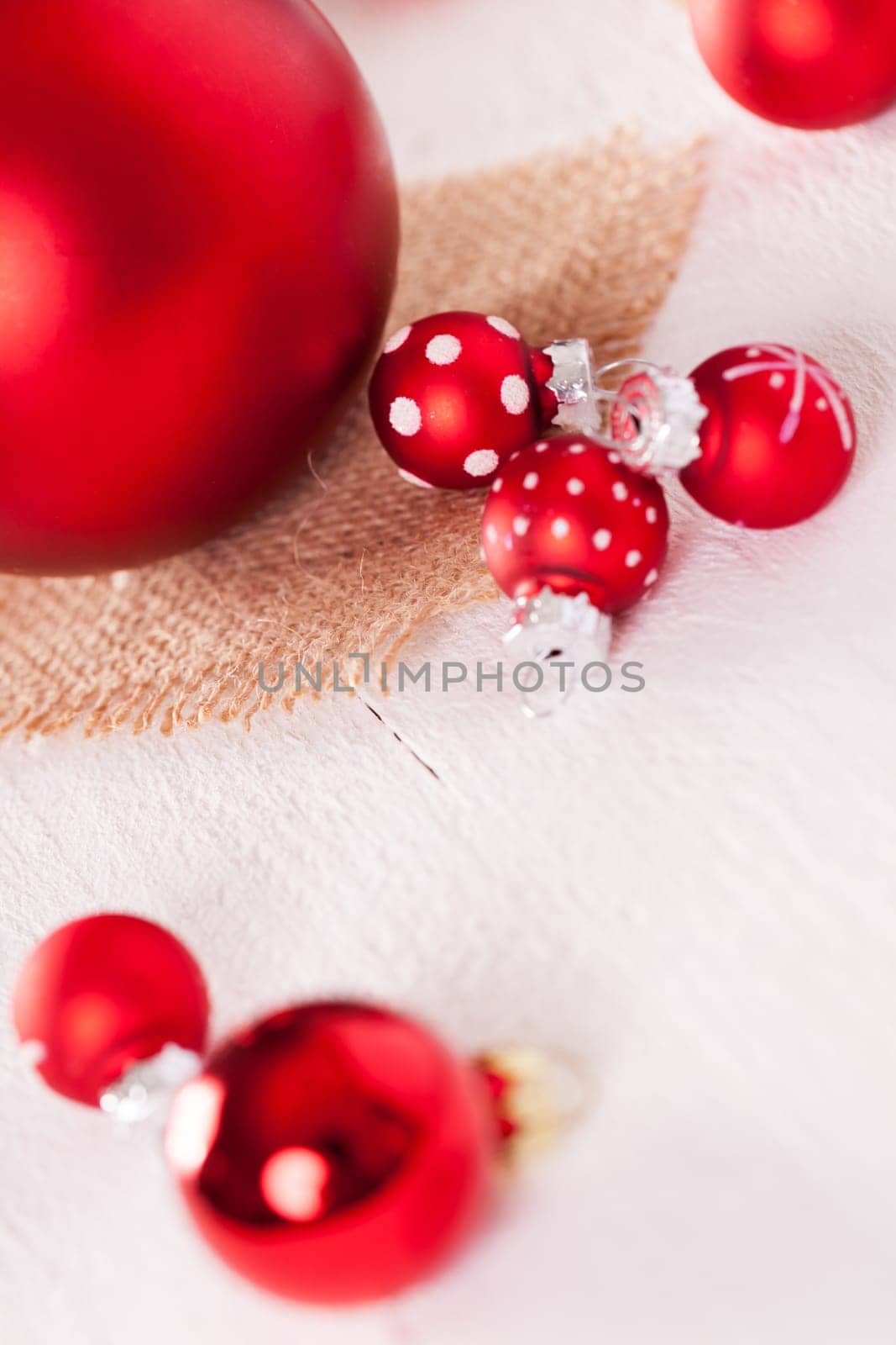large and small red Christmas tree balls on a wooden board with a jutesack as a close-up