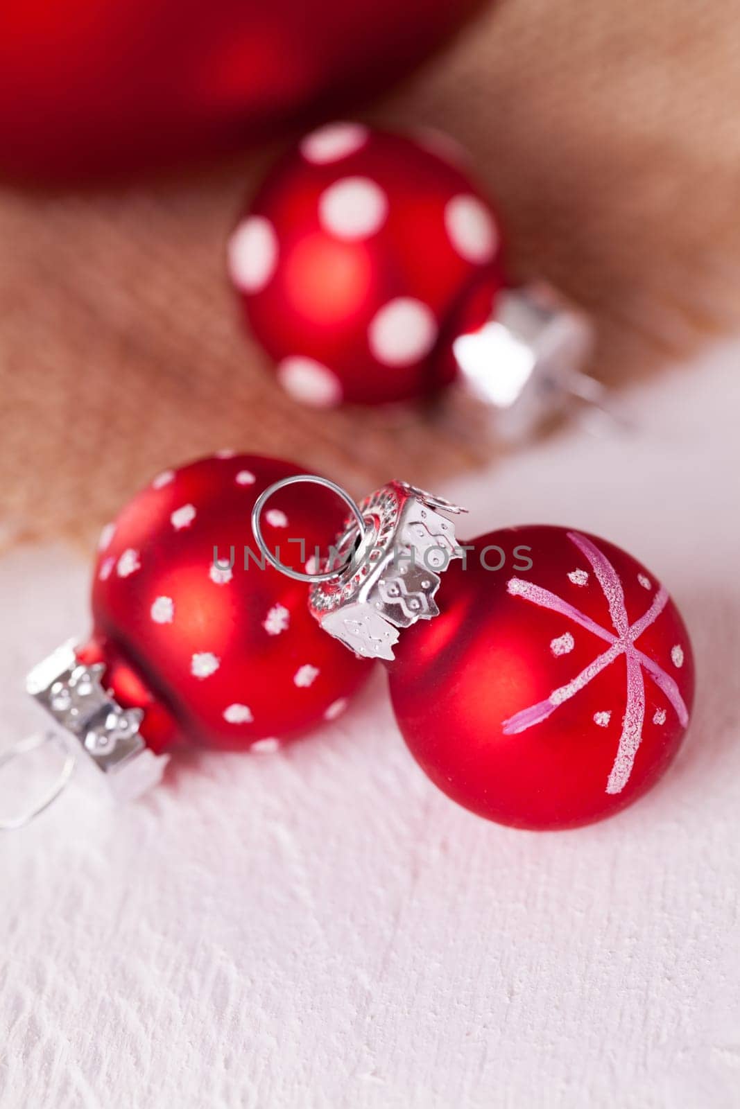 large and small red Christmas tree balls on a wooden board with a jutesack as a close-up