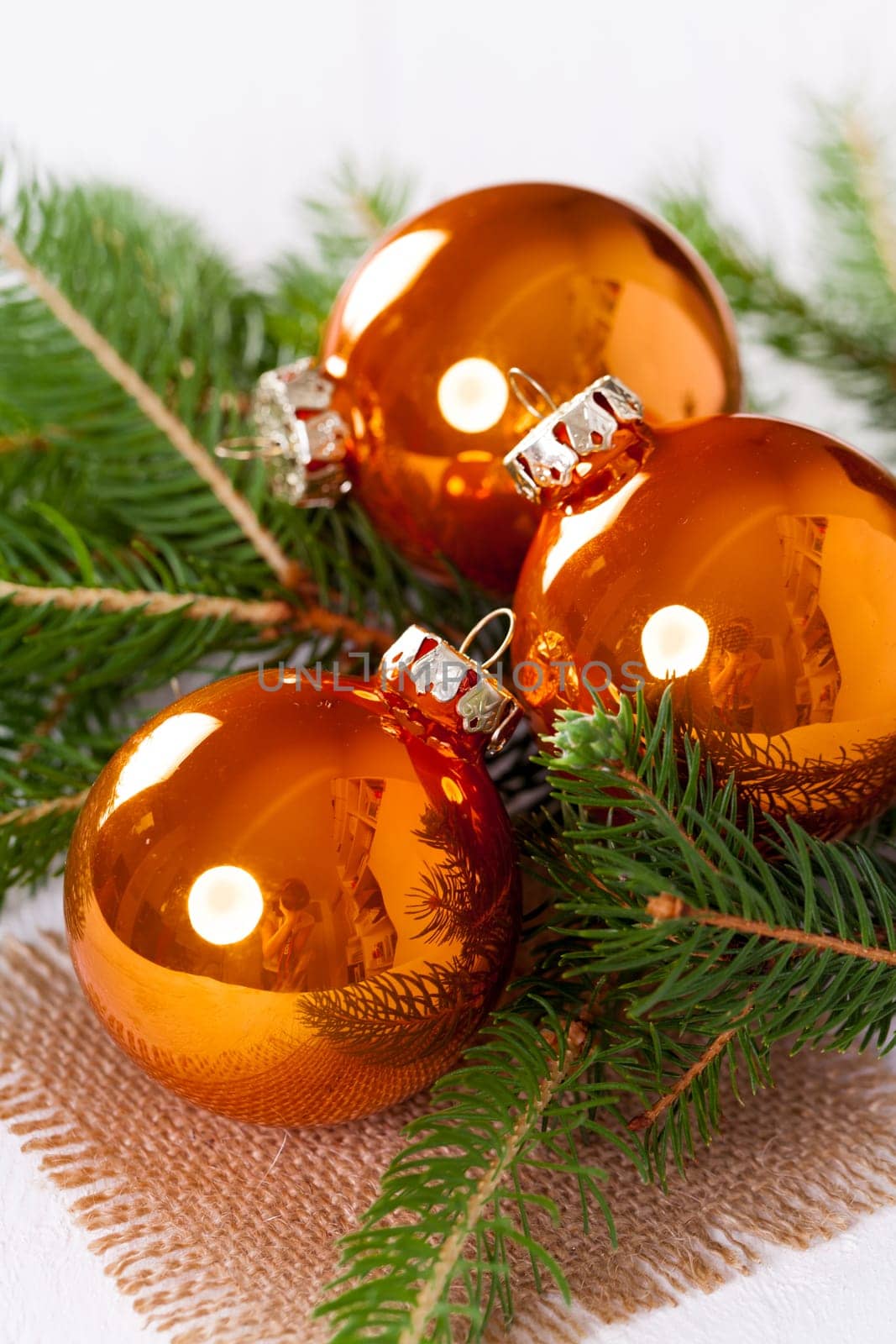 Shiny orange glass balls Christmas balls with green twigs on a jute sack as a close-up