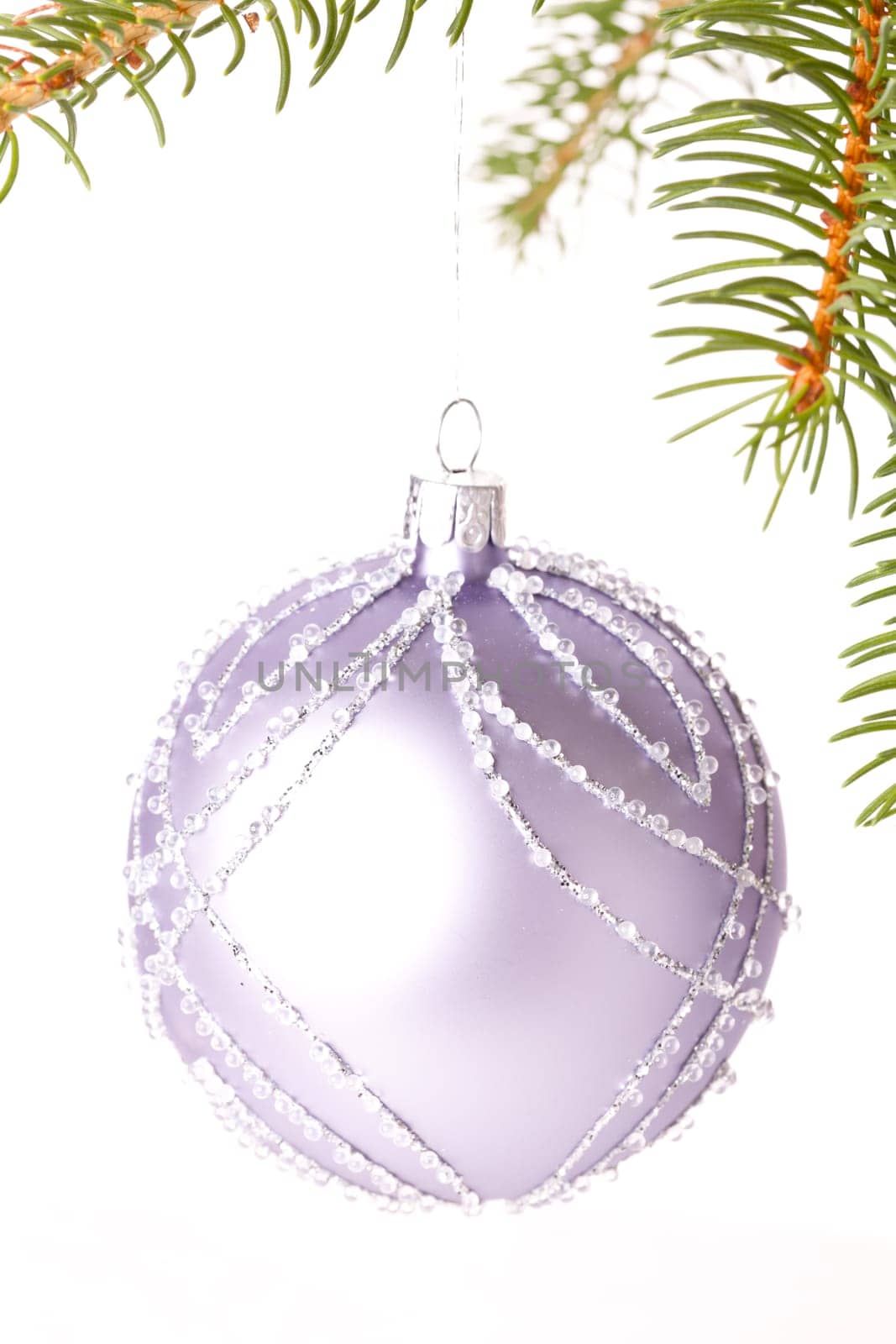 Traditional Christmas ball hung on a green fir branch isolated against a white background