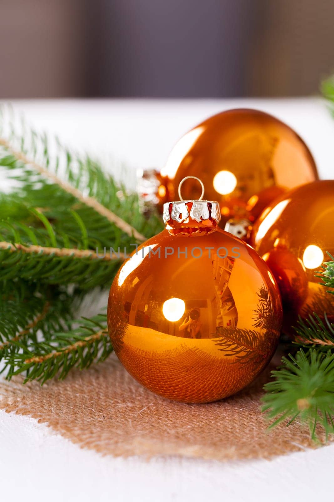 Shiny orange glass balls Christmas balls with green twigs on a jute sack as a close-up