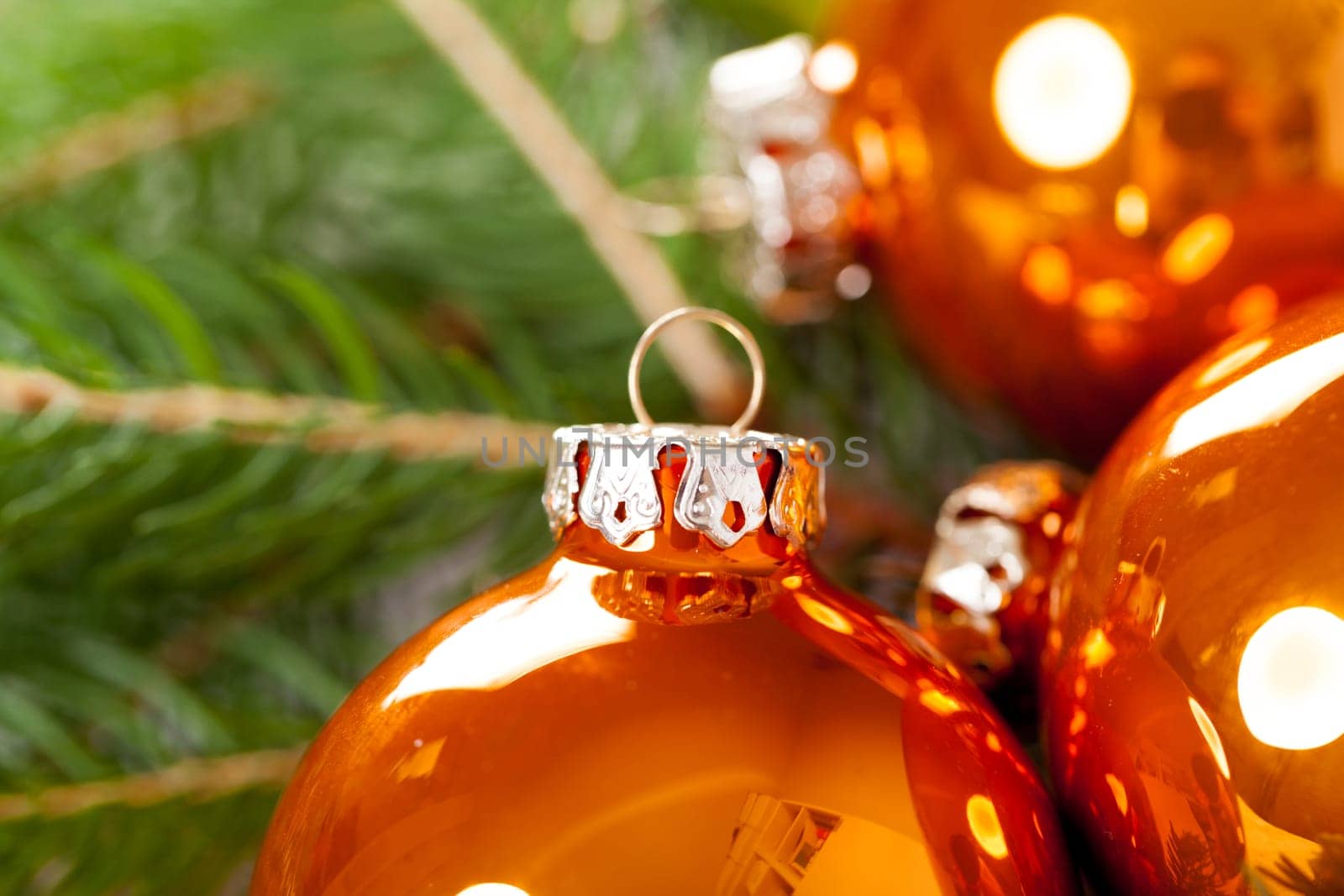 Shiny orange glass balls Christmas balls with green twigs on a jute sack as a close-up