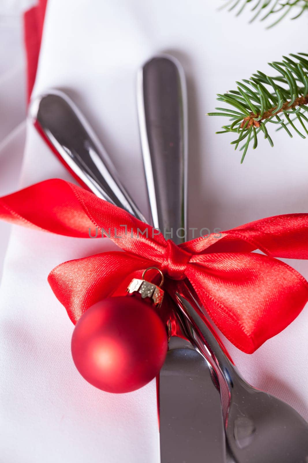 Romantic Christmas table with red balls and red bow with cutlery knife and fork on a napkin