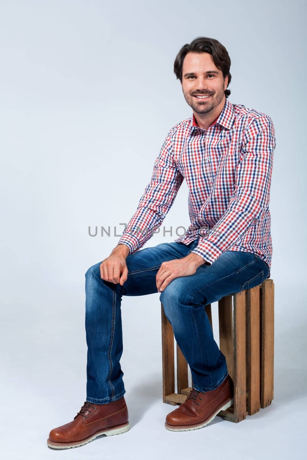 Young man with beard and dark hair with jeans and carated shirt