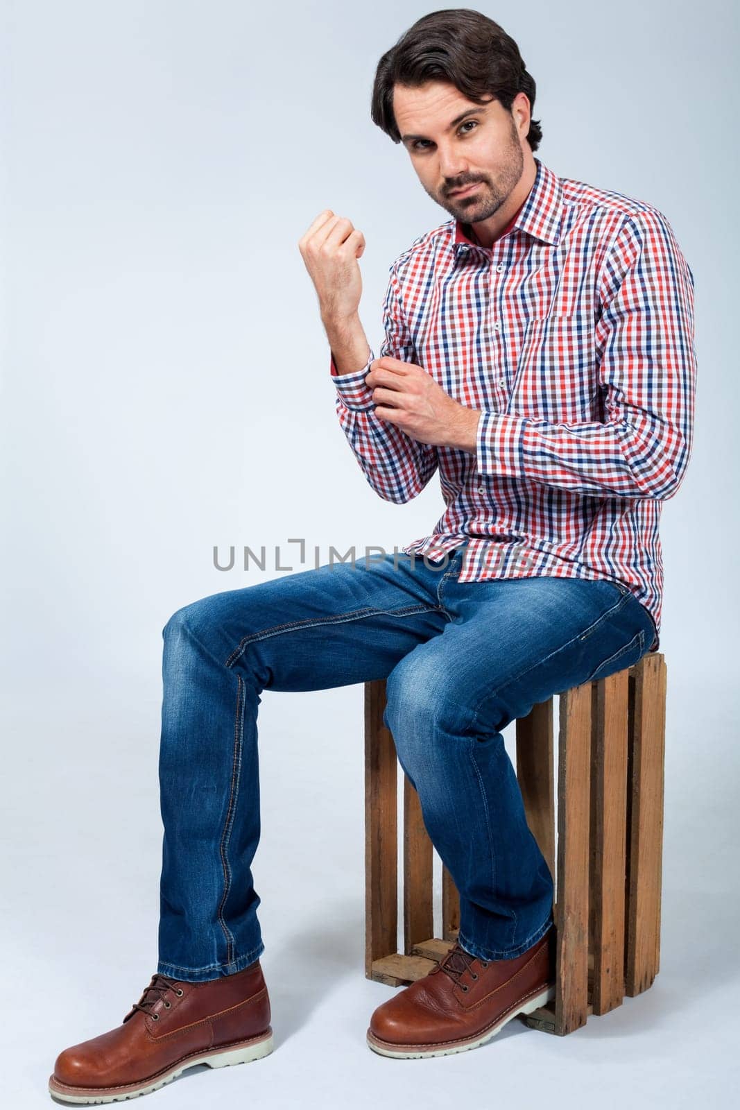Young man with beard and dark hair with jeans and carated shirt