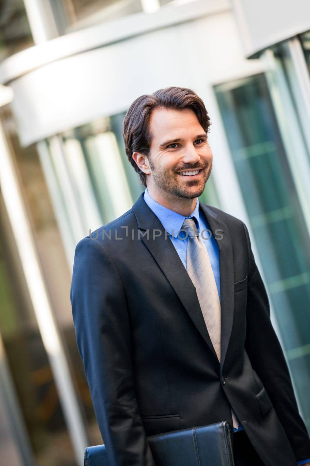 Young trendy businessman in front of a business building successfully with beard and dark hair
